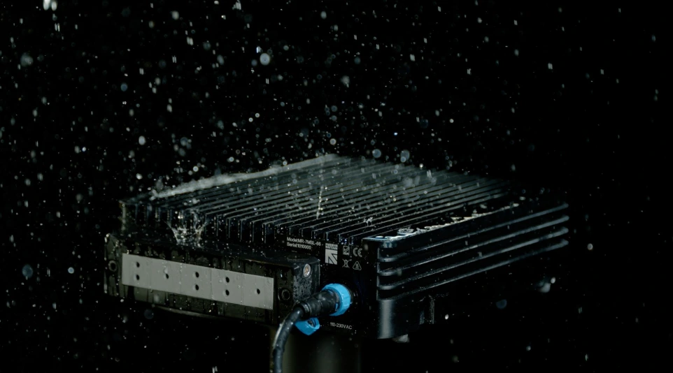 A fanless Tranquil rugged PC being subjected to a heavy water spray, highlighting its waterproof capabilities.